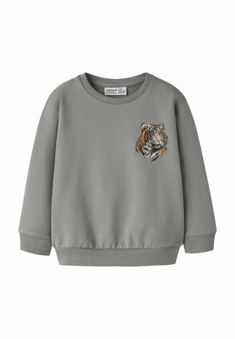 Pelēks džemperis ar apaļu izgriezumu un rievotām aprocēm. Kreisajā krūtīs izšūta tīģera galva. Mīksts kokvilnas maisījuma materiāls.