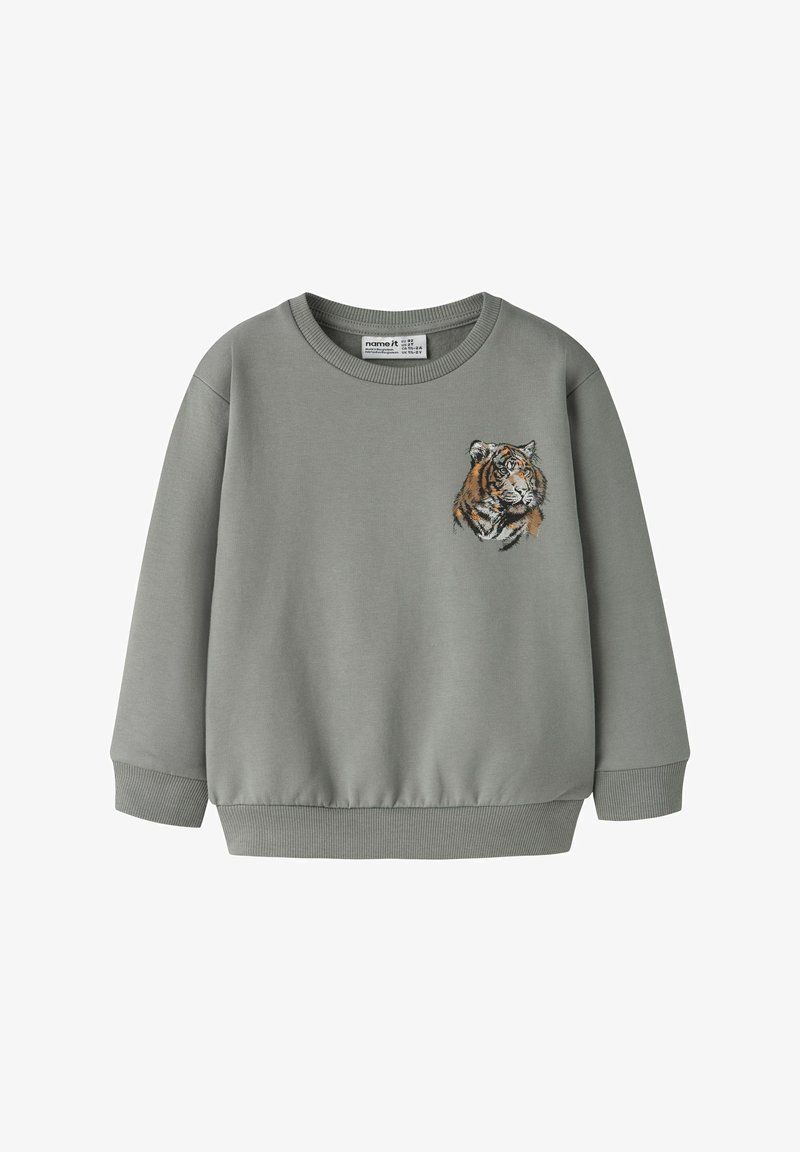 Grå genser med rund hals og ribbestrikkede mansjetter. Har et brodert tigerhode på venstre bryst. Mykt stoff i bomullsblanding.