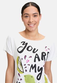 Biała koszulka z krótkim rękawem z czarnym napisem "Ty JESTEŚ moim", z grafikami limonek i różowymi akcentami.