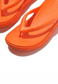 Oranje flip-flops met een textuur voetbed en een thongsandalen ontwerp. Gemaakt van rubber, met een gladde afwerking en een lichtgewicht constructie.
