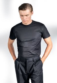 Svart t-shirt med rund hals i mjukt tyg, matchad med skräddarsydda svarta byxor med klassiska veck och sidofickor. En enkel, skräddarsydd look.