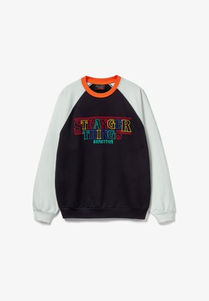 Felpa nera con maniche raglan grigio chiaro e colletto arancione. Presenta ricami colorati con le scritte "STRANGER THINGS" e "BENETTON" sul davanti.