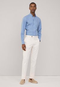 Blauw-witte gingham button-down shirt gecombineerd met crèmekleurige broeken en beige instappers, met een getailleerde pasvorm en standaard kraag.