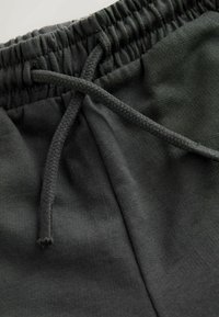 Pantaloni de trening din bumbac gri închis, cu talie elastică prevăzută cu șnur împletit și textură netedă.