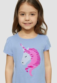 Lichtblauw t-shirt met pofmouwen, versierd met een geborduurde eenhoorn in wit en roze, waarbij de manen worden benadrukt met gestreepte patronen.