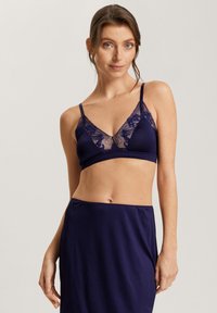 Tummansininen bralette, jossa on herkkä pitsireuna, pehmeä kangas, V-kaula-aukko ja säädettävät hihnat, yhdistettynä samanväriseen tummansiniseen hameeseen.