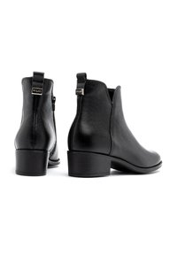 Czarne skórzane botki sięgające za kostkę o gładkiej powierzchni, okrągłym nosku, niskim obcasie i bocznym zamku błyskawicznym. Posiadają małą metkę marki na obcasie.