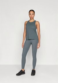 Sportoutfit bestående av en mörkgrå linne och matchande leggings med en slät, elastisk textur. Har minimalistisk design utan mönster.
