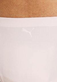 Puma sømløse undertøy i lys rosa, med en myk midjebånd og en subtil hvit logo. Glatt, elastisk stoff med en pustende tekstur.