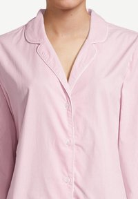 Maglietta da pigiama a righe rosa e bianche con colletto a scollo a V, bottoni frontali e maniche lunghe, realizzata in tessuto leggero e traspirante.