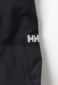 Schwarze Stoffhosen mit einem strukturierten unteren Abschnitt, ausgestattet mit einem weißen "HH"-Logo auf der oberen rechten Seite. Hergestellt aus strapazierfähigen Materialien.