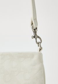 Borsa bianca con texture, caratterizzata da un design a motivo sottile, con tracolla in pelle e hardware metallico per la chiusura e l'attacco.