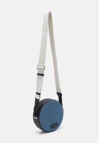 Kulatá crossbody taška s přední stranou z modrého denimu, černým umělým koženým dnem a bílým nastavitelným popruhem s embosovaným textem. Zapínání na zip.