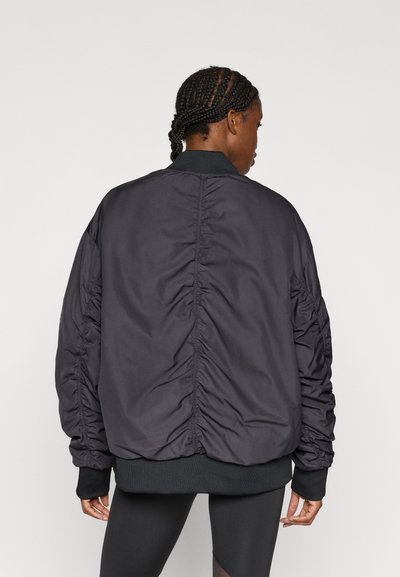 Μαύρο bomber μπουφάν με υφή και ρυτιδωτή πλάτη, ριμπ μανσέτες και μέση, σχεδιασμένο για άνετη εφαρμογή χωρίς εμφανή κουμπώματα.
