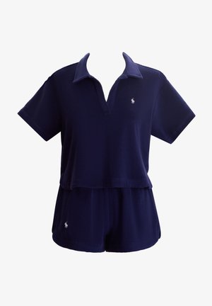 Μπλε ναυτικό, μπλουζάκι πόλο με κοντά μανίκια, ντεκολτέ σε σχήμα V και διακοσμητικό λογότυπο· συνοδευόμενο από ταιριαστά σορτς από μαλακό, φλις ύφασμα.