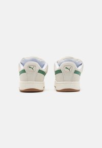 Bež Puma suede tenisice s zelenim naglascima. Imaju teksturiranu gumenu potplat i podstavljen ovratnik za udobnost. Minimalistički dizajn.