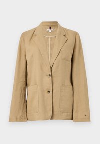 Blazer in lino marrone chiaro, design sartoriale, colletto a revers, due tasche frontali, chiusura a due bottoni e discreto accento di marca sulla manica.