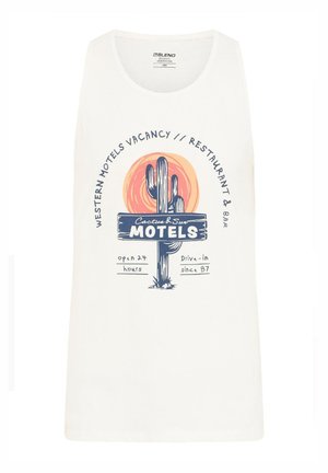 Débardeur blanc présentant un design graphique avec un cactus et un soleil, texte à propos d'un motel, avec des couleurs bleu, orange et noir. Tissu doux.