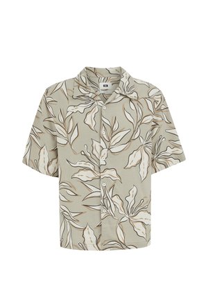 Chemise à manches courtes avec boutons, fond beige et motif abstrait de feuilles en brun, blanc et noir.