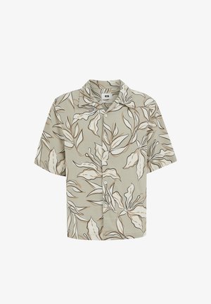 Chemise à manches courtes avec boutons, fond beige et motif abstrait de feuilles en brun, blanc et noir.