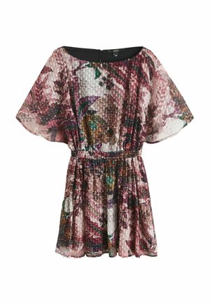Femme portant une robe courte et transparente à motif floral avec une taille élastique, des bottes hautes en daim marron clair, et tenant un sac à main marron clair à franges.
