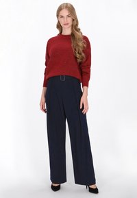 Rode textuur sweater met een ronde hals, gecombineerd met hooggeplaatste marineblauwe wijde pantalons met een riemsluiting.