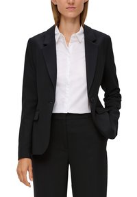 Czarny żakiet z klapkami, na jeden guzik i dwoma przednimi kieszeniami, noszony na białej koszuli z kołnierzykiem. Gładki materiał, dopasowany krój.