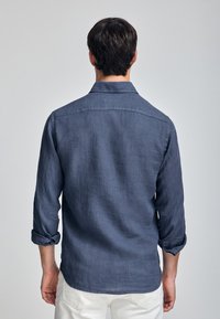 Marineblauwe linnen shirt met een kraag, lange mouwen met manchetten en een ontspannen pasvorm, van achteren weergegeven. Soepele textuur.