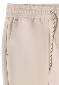 Pantalon de jogging beige en tissu texturé, avec taille élastique et cordon de serrage. Dispose de deux poches latérales ornées d'accents métalliques argentés.