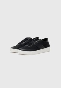 Zwarte leren sneakers met een gladde afwerking, voorzien van ton-sur-ton stiksels, witte rubberen zolen en platte veters. Minimalistisch ontwerp en een lage profiel.