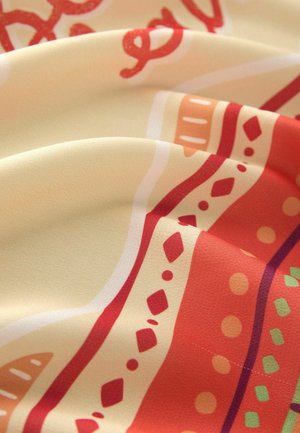 Printed fabric featuring a cream base with colorful patterns of red, orange, and green. Texture appears smooth and slightly glossy.