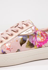 Rosa sneakers med blommönster har en satinliknande ovandel med metalliska accenter, runda snören och en vit gummisula, med livfulla blomsterdesigns.