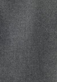 Gros plan d'un tissu gris à texture tissée fine montrant des variations subtiles de nuances et de motifs.