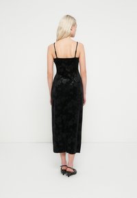 Svart fløyels midi-kjole med blomstertrykk, smal passform, justerbare spaghettistropper, glatt tekstur, med rett kant og uten pynt.