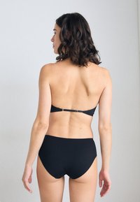 Svart bikinitopp, med en enkel halterneck med justerbar ryggspänne och högmidjade underdelar. Slät tyg, minimalistisk design.