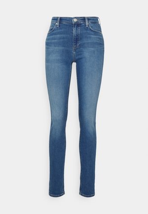 Jeans skinny in denim blu medio. Design a vita alta con una texture liscia, tasche anteriori e posteriori a scomparsa e dettagli di sbiadimento subtile.