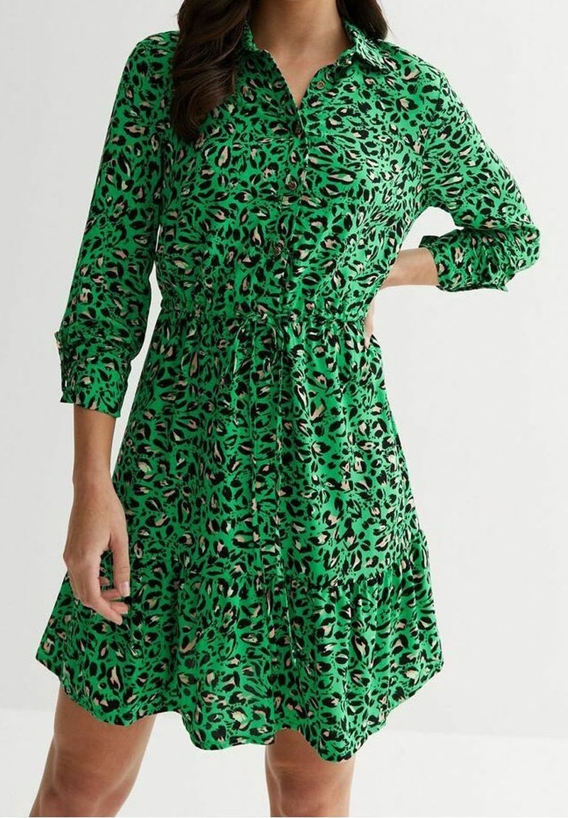 Abito verde con bottoni, caratterizzato da una stampa leopardata, vita arricciata e maniche lunghe, con una gonna a strati e tessuto leggero.