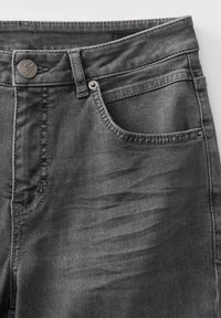 Sezione frontale superiore di un paio di jeans in denim nero sbiadito che mostra dettagli di bottone, passante per cintura, cuciture e tasca.