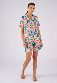 Conjunto de pijama de manga corta con un colorido patrón floral, que presenta hojas y flores multicolores en una tela suave. Incluye pantalones cortos a juego.
