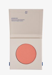Rubor en polvo en un recipiente circular, color coral suave con textura mate; alojado en un compacto cuadrado de crema con acento azul.