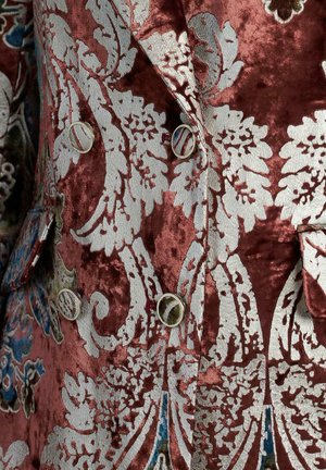 Samtjacke in tiefem Burgunderrot mit kunstvoller silberner Blumenstickerei. Verfügt über ein doppelreihiges Design und dekorative Knöpfe.