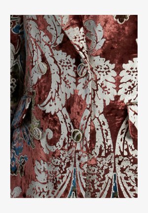 Giacca di velluto in burgundy intenso con ricami floreali argentati intricati. Presenta un design doppiopetto e bottoni decorativi.