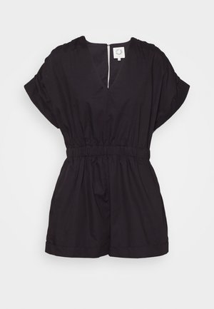 Combinaison noire à manches courtes avec taille élastique, encolure en V et ourlets repliés sur un fond blanc uni.