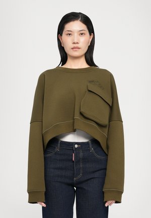 Sweatshirt cropped olive avec des manches longues, une poche devant et des détails de couture contrastants. Porté sur un jean bleu foncé.