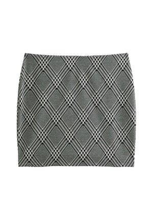 Mini-jupe à carreaux noire et blanche présentant une coupe ajustée, un tissu texturé et un motif en losanges avec des lignes et des formes qui se croisent.