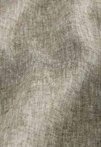 Tela de color marrón claro con texturas sutiles y una apariencia suave y tejida, que muestra hilos finos y un acabado ligeramente irregular.