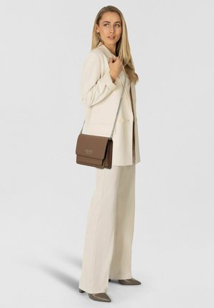 Brown leather crossbody bag with a flap and gold logo. Features a silver chain strap, rectangular shape, smooth texture, and minimalist design.