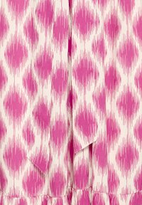 Tissu rose et blanc avec des motifs abstraits en forme de losange répétés et des stries verticales, présentant un détail de nœud noué près du centre en bas.