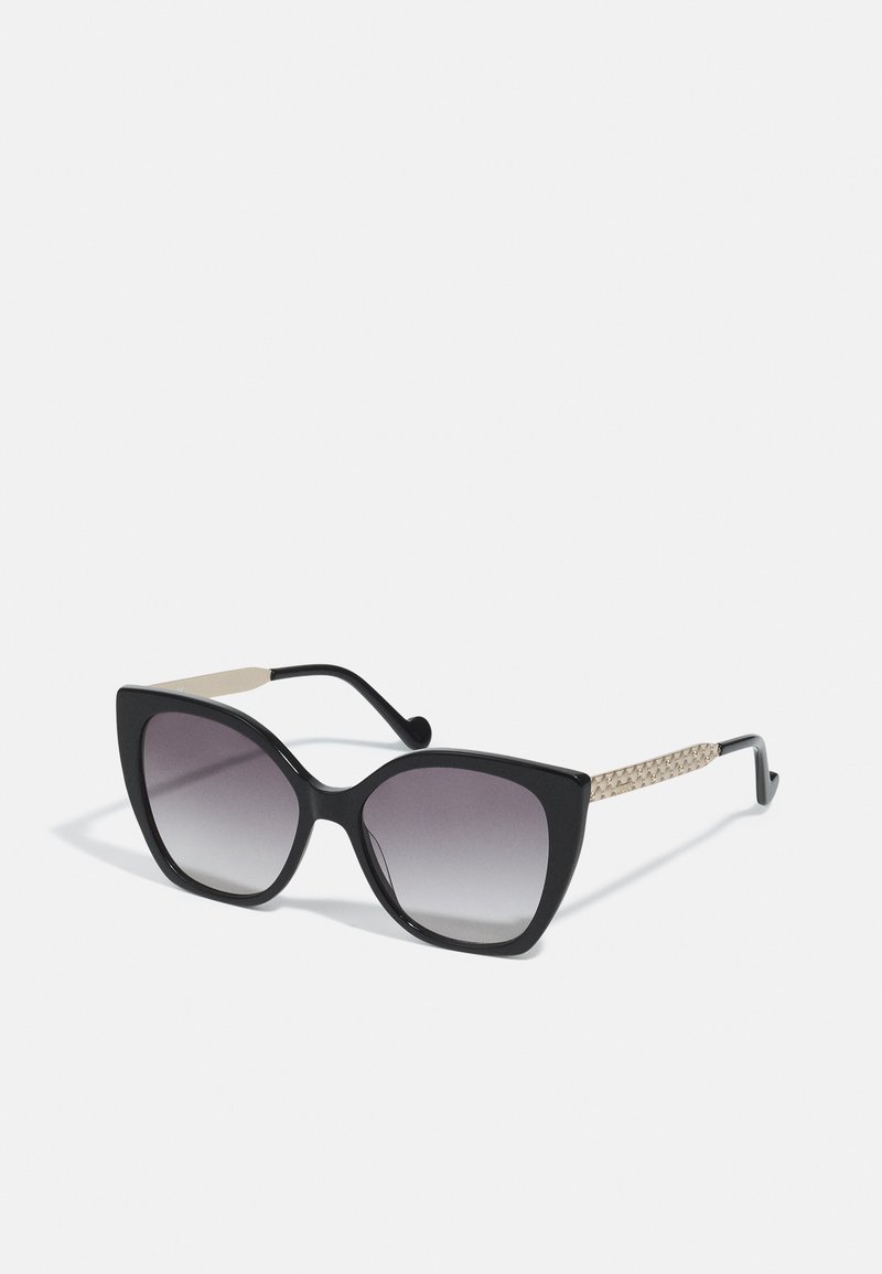 Cat-eye sunglasses with a black frame, gradient lenses, and a textured cream and black woven accent on the temple.