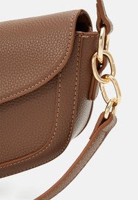 Sac à main en cuir synthétique texturé marron avec un rabat, accents en métal doré, et une bandoulière détachable. Présente des coutures contrastées.